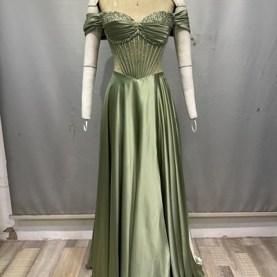 Vestido longo verde com pedraria exibido em manequim.