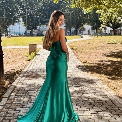 Mulher de costas usando vestido verde longo em pedra ao ar livre