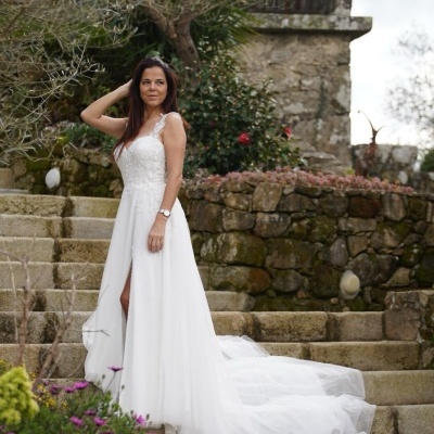 Mulher com vestido de noiva branco longo com cauda numa escadaria de pedra exterior
