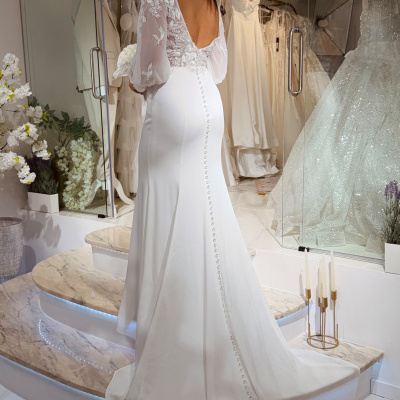 Vestido de noiva branco com mangas de renda florais e saia longa visto de costas.