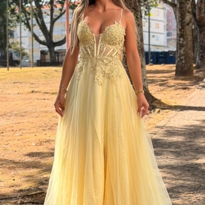 Mulher com vestido longo amarelo claro com bordados de renda e saia transparente ao ar livre