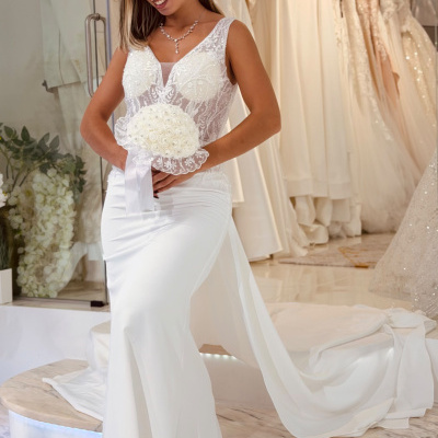 Mulher em vestido de noiva branco com bouquet branco em loja de vestidos