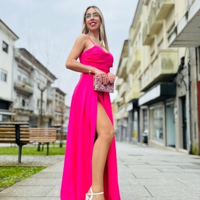 Mulher com vestido rosa fúcsia longo e sandálias brancas em passeio urbano