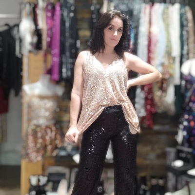 Mulher com top rosa brilhante e calças pretas brilhantes em loja de roupa