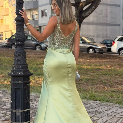 Vestido de cetim verde claro com corpete transparente decorado com pérolas, em ambiente urbano exterior