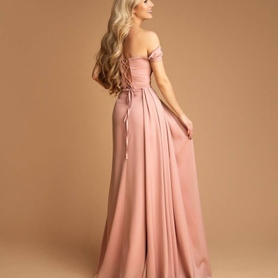 Mulher loira de costas com vestido longo rosa fluido e decote ombro a ombro