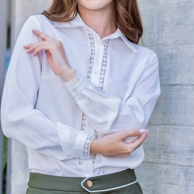 Blusa branca feminina com detalhes em renda e calças verdes com botão dourado