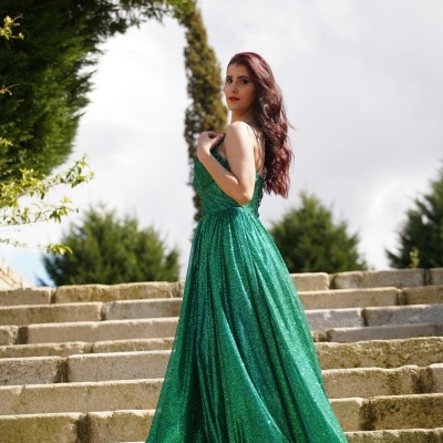 Mulher com vestido verde cintilante em escadaria exterior