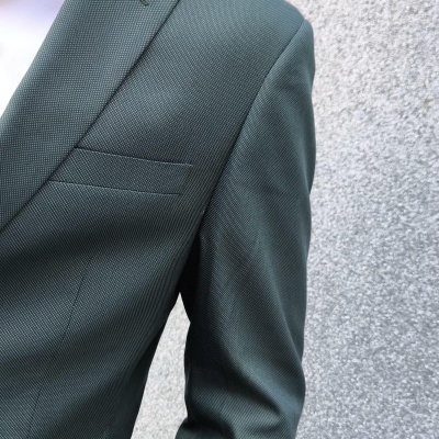 Fato cinza escuro com padrão discreto e camisa branca, vista parcial no corpo com fundo cinza texturizado