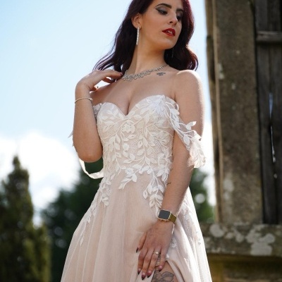 Vestido de noiva bege com renda branca floral, decote coração e mangas caídas, em cenário exterior