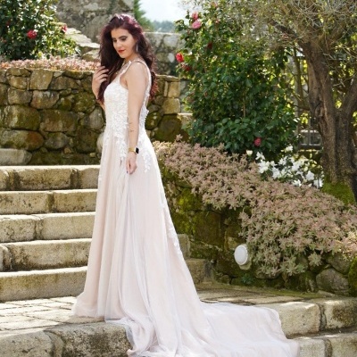 Vestido de noiva branco longo com cauda em escadas de pedra num jardim