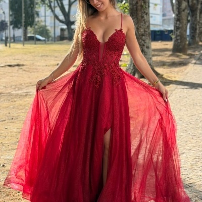 Vestido vermelho comprido com alças finas e rendas, usado por mulher num parque.