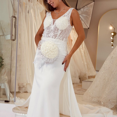 Mulher com vestido de noiva branco com renda e bouquet redondo, em loja de vestidos de noiva.