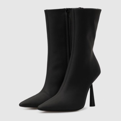 Botas pretas de salto alto fino com bico fino em fundo cinzento