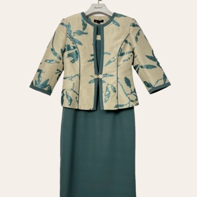 Conjunto de vestido verde escuro e casaco bege com padrão folhado verde.