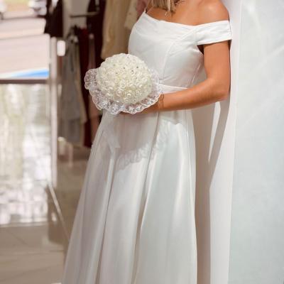 Mulher com vestido de noiva branco e bouquet de flores brancas, em ambiente interno