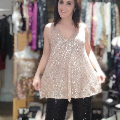 Mulher vestindo blusa champanhe brilhante e calças pretas brilhantes em loja de roupa