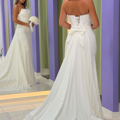 Vestido de noiva branco com laço e cauda em ambiente com paredes lilás