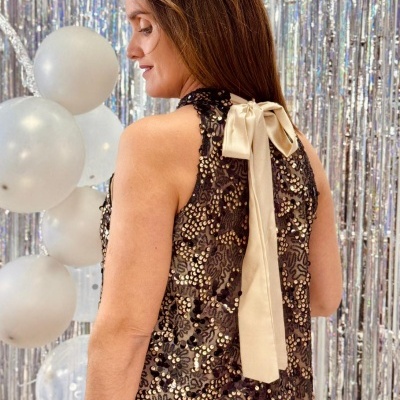 Vestido de festa preto com lantejoulas douradas e laço creme nas costas