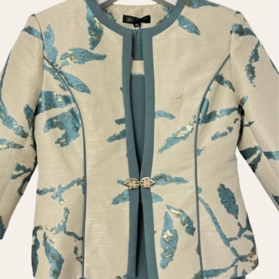 Conjunto casaco bege com padrão azul e dourado e vestido azul-petróleo pendurado em cabide