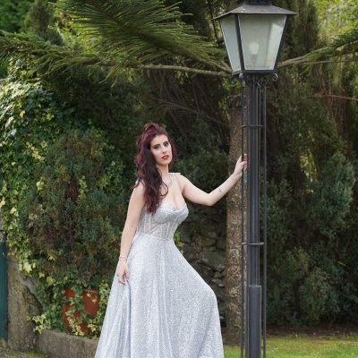 Vestido longo prateado com brilho usado por mulher junto a candeeiro ao ar livre