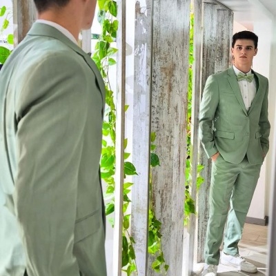 Homem com fato verde-clarinho em frente a espelho numa divisão interior clara