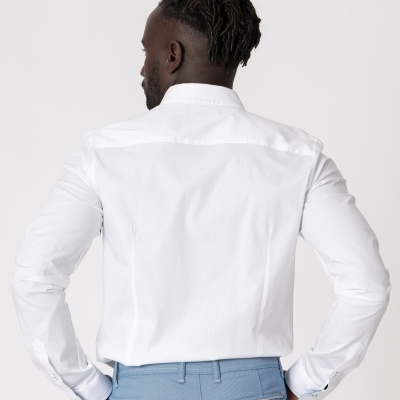 Homem de costas com camisa branca de manga comprida e calças azuis