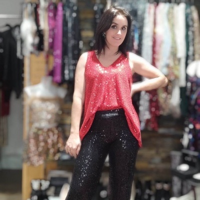 Mulher com blusa vermelha brilhante e calças pretas brilhantes numa loja de roupa