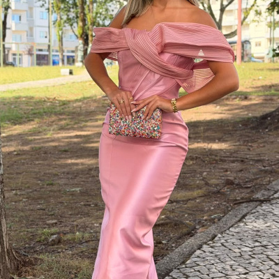 Mulher com vestido rosa acetinado, clutch colorida e sandálias brancas de salto ao ar livre