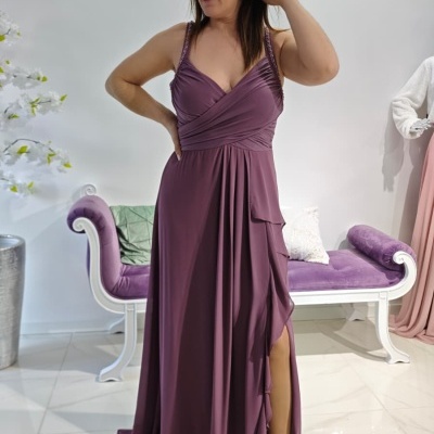 Vestido longo roxo com alças finas e racha lateral, sapatos rosa claro e banco roxo ao fundo