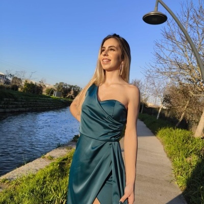 Mulher com vestido verde-azulado num passeio junto a um canal fluvial