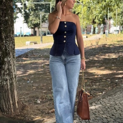 Mulher com colete azul escuro, jeans largos e bolsa castanha ao ar livre