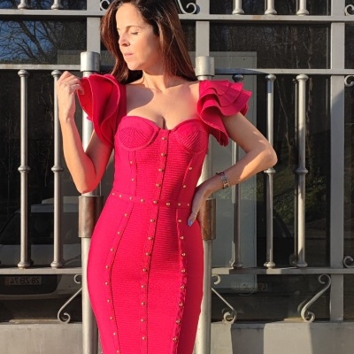 Mulher a usar vestido justo vermelho com babados e botões dourados, sandálias pretas, em exterior