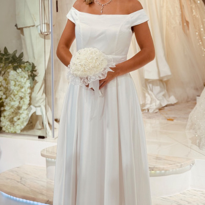 Mulher de vestido de noiva branco com bouquet branco em showroom