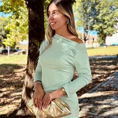 Mulher com vestido verde menta e clutch dourada ao ar livre