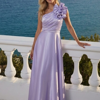 Mulher a usar vestido lilás acetinado com adorno floral no ombro, em varanda branca com vista para o mar azul