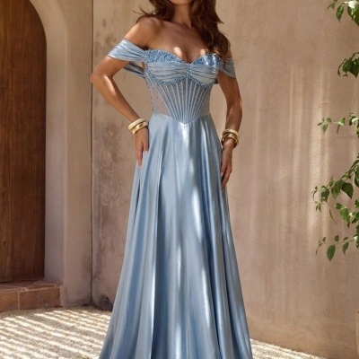 Mulher com vestido longo azul claro de cetim com corpete bordado em ambiente com parede clara e porta de madeira