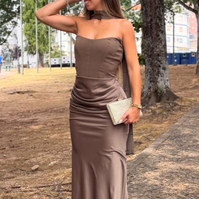 Vestido longo castanho brilhante com decote tomara que caia e carteira dourada ao ar livre