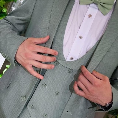 Fato de três peças verde claro com gravata borboleta em ambiente com plantas