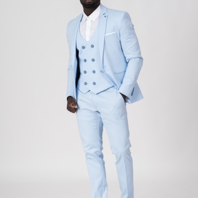 Homem vestido com fato azul claro composto por blazer, colete, calças, camisa branca e sapatos azuis escuros com sola branca