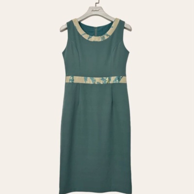 Vestido verde-azulado com detalhes bege e azul pendurado num cabide branco.