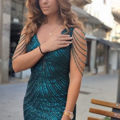 Vestido azul esverdeado brilhante com detalhes de tiras nas mangas em ambiente urbano