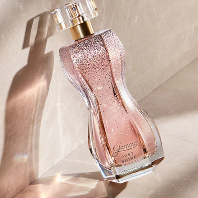 frasco de perfume rosa brilhante com tampa transparente sobre superfície bege