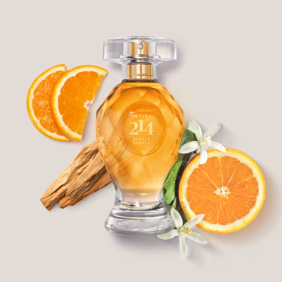 Frasco de perfume âmbar com laranja, madeira e flores brancas ao lado