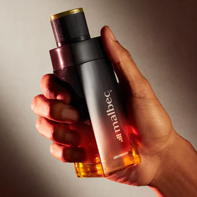 Frasco de perfume Malbec de O Boticário segurado por uma mão.