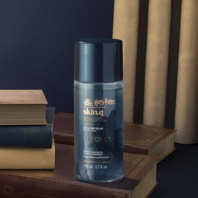 Frasco de água micelar Harry Potter skin.q sobre livros antigos em fundo azul escuro