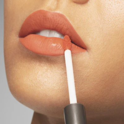 Lábios com batom terracota sendo aplicado com aplicador