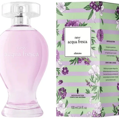 Frasco de perfume rosa translúcido com tampa transparente ao lado de caixa verde com flores lilases e brancas