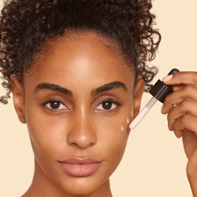 Mulher a aplicar corretor líquido no rosto com conta-gotas