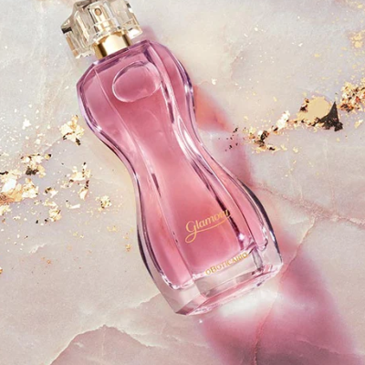 Frasco de perfume rosa com tampa transparente em superfície marmoreada
